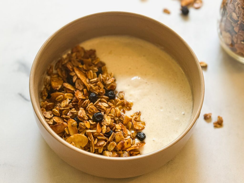 Salty-Sweet Blueberry Almond Granola as a topping for dairy free yogurt in a bowl.