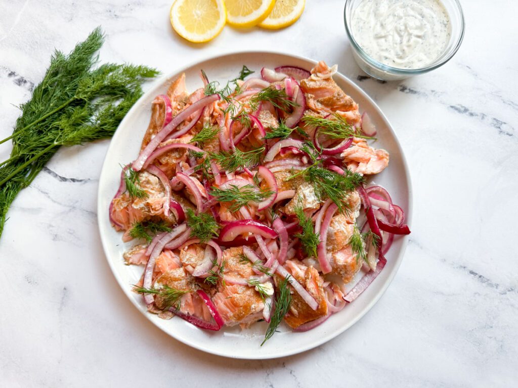 slow-roasted salmon on a serving platter topped with onions and fresh dill